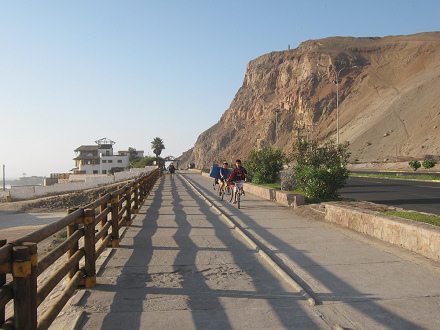 Laucho-Strand, der Fahrradweg mit
                        Fahrradfahrern mit Surfbrettern unterm Arm, und
                        der Morroberg im Hintergrund