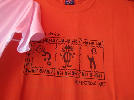 T-Shirt mit dem Design von
                                Geoglyphen, Nahaufnahme: Da waren eine
                                Katze, ein Ausserirdischer mit Antennen
                                auf dem Kopf, und eine Ende.