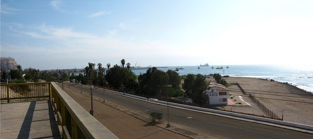 Chile-Allee, Sicht von der Br�cke �ber
                            die Eisenbahnlinie auf die leere
                            Porcel-Allee, auf den Morroberg, den Hafen
                            von Arica, das Hotel "Zur Bucht"
                            (hotel Bah�a) und den Chinchorrostrand,
                            Panorama
