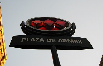 Waisenkinderstrasse (calle Hu�rfanos),
                          der Eingang zur U-Bahnstation
                          "Zentralplatz" (Waffenplatz, plaza
                          de Armas), das Logo der U-Bahn von Santiago de
                          Chile mit drei roten Trapezen