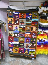 Wandteppich mit kleinen Motiven:
                              M�nner, Frau mit Kind auf dem R�cken,
                              Vulkan, Tiere etc.