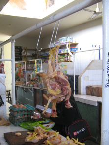 Chilca, mercado, una gallina abierta, y
                          atr�s lee una mujer una revista de moda
                          gringa