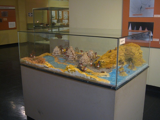 Die Vitrine mit einem Steinzeit-Modell der
                      J�ger und Sammler und der ersten Landwirtschaft,
                      Sicht halb von der Seite