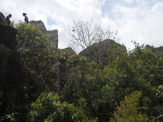 Sicht auf den Gipfel von Huaynapicchu mit dem Steinbruch mit geschnittenen Gigasteinen, die einen zweiten Tunnel bilden 04