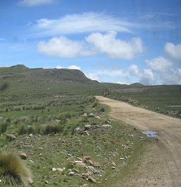 Der Feldweg mit Pf�tzenschlagloch und
                        Wolkenbild
